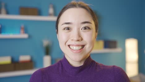 Standing-serious-Asian-woman-raises-her-head-to-camera-and-smiles.